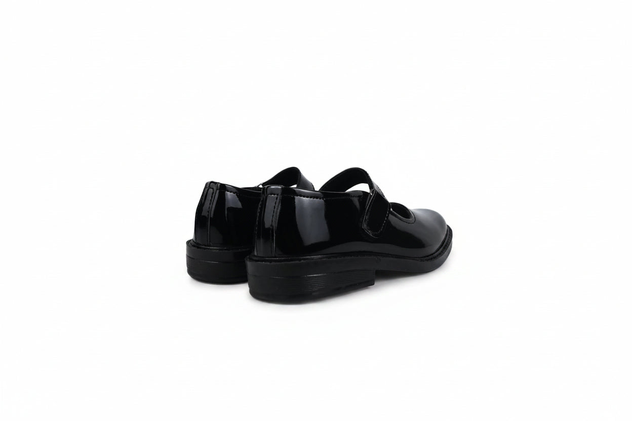 A pair of black patent leather Mary Jane shoes with strap closures, shown from a side-rear angle against a white studio backdrop.