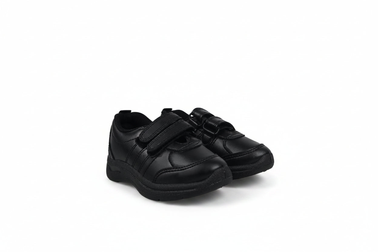 A pair of black children's low-top sneakers with hook-and-loop strap closures, photographed on a light gray studio background.