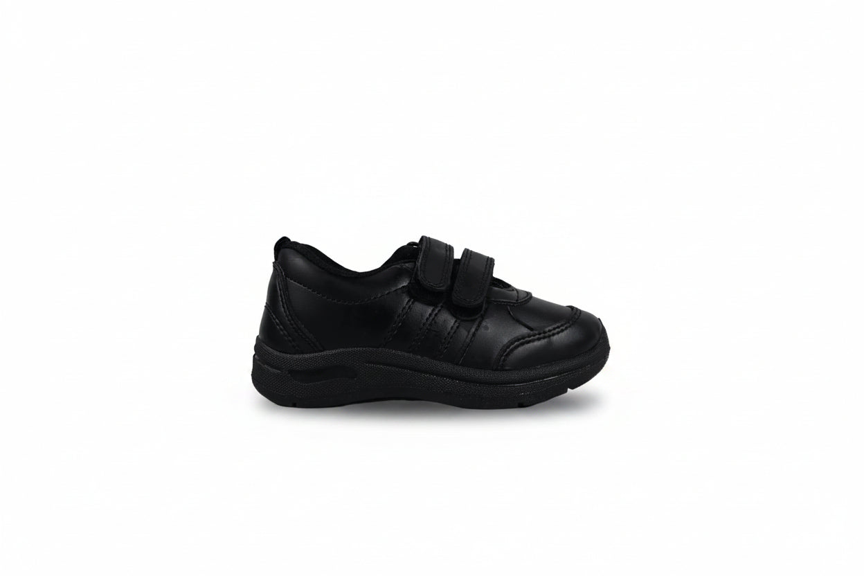 A single black low-top shoe with two hook-and-loop strap closures, shown in profile against a light gray studio backdrop.