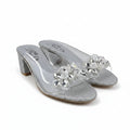 A pair of silver glitter mule sandals with clear rhinestone floral embellishments on the straps, shown against a plain white background.
