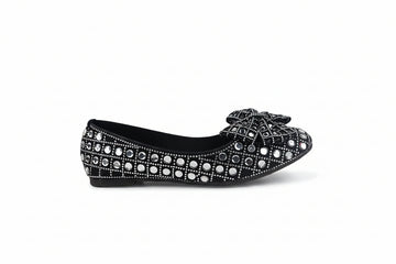 A single black flat shoe decorated with rows of silver rhinestones and a matching rhinestone-embellished bow on the toe, shown against a plain white background.