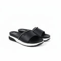 A pair of black slide sandals with white platform soles and a silver chain detail across the top, displayed on a light gray background.