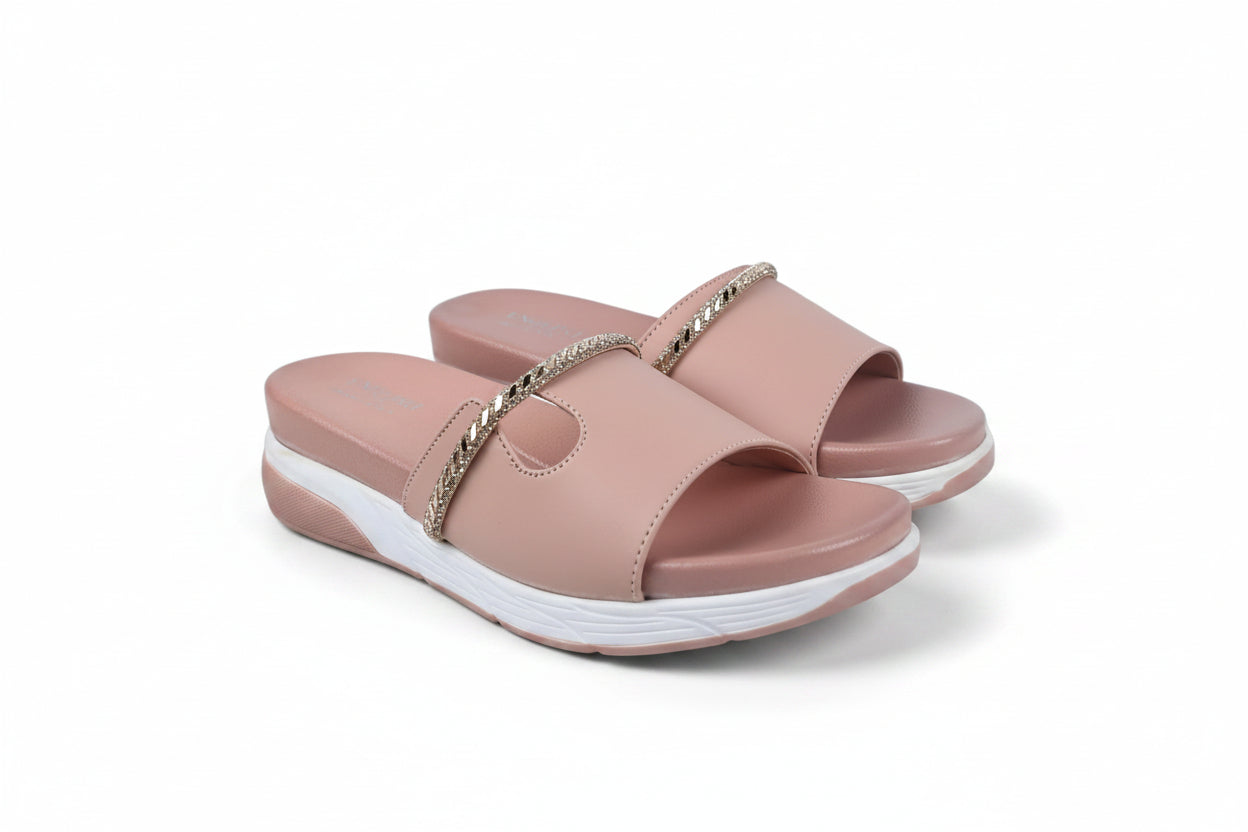 A pair of women's platform slide sandals in a dusty pink color, featuring a metallic gold chain detail across the strap and a thick white platform sole.