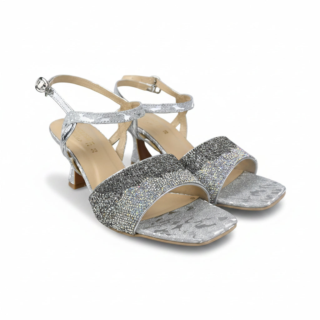 A pair of women's heeled sandals with silver glittery straps and a snakeskin-patterned silver toe strap, featuring beige insoles and ankle straps, set against a plain white background.