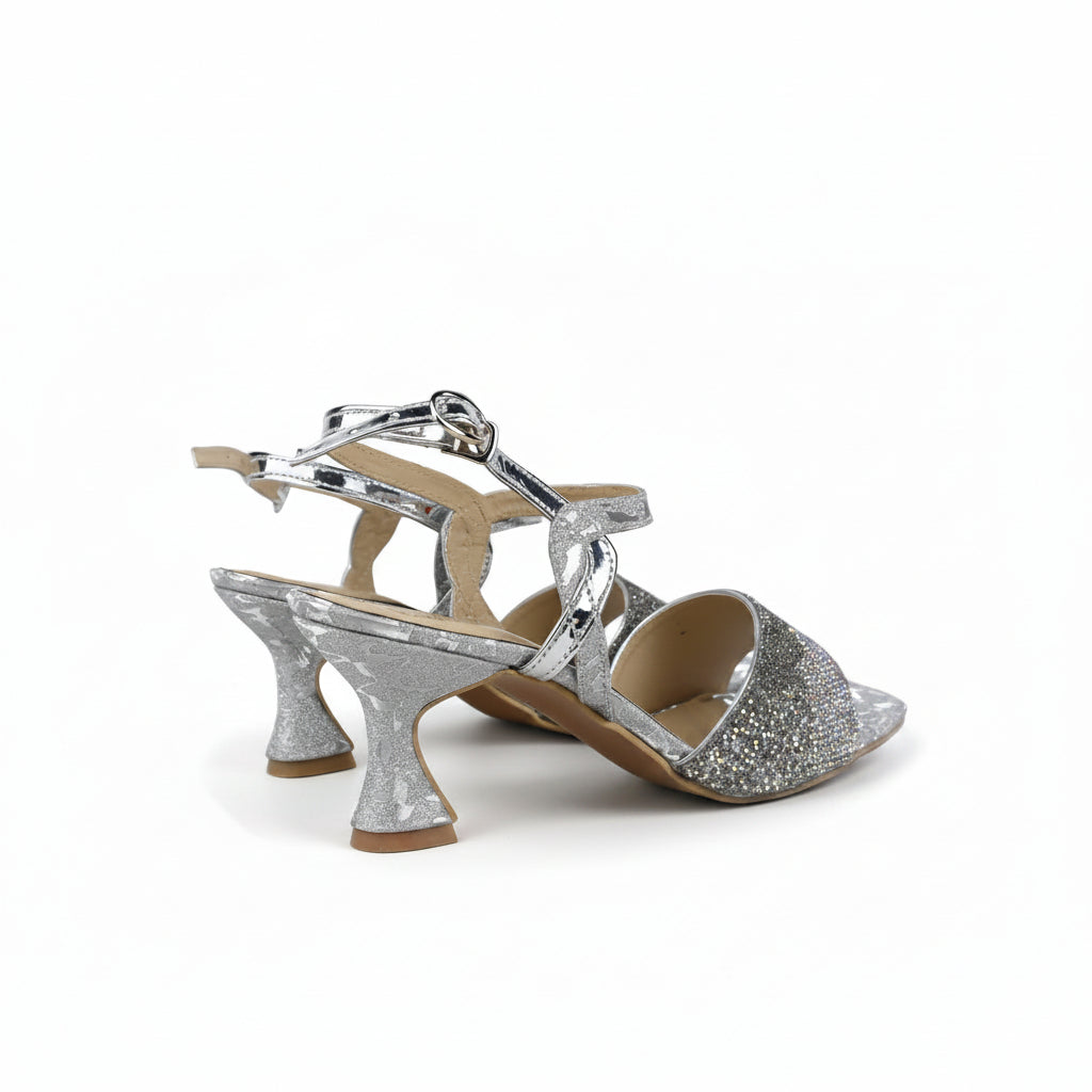 A pair of women's heeled sandals with silver glittery toe caps, ankle straps, and flared block heels, shown on a light gray background.