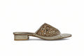 A single women's heeled mule sandal in metallic gold, featuring an intricate geometric patterned upper and a low block heel, shown against a neutral light gray background.
