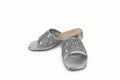 A pair of metallic silver slide sandals embellished with rhinestones across the open toe straps, shown on a plain white background.