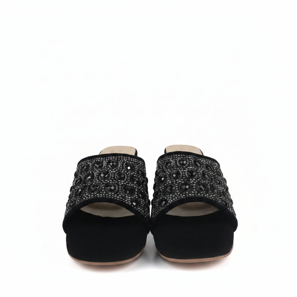 A pair of black velvet slide sandals embellished with intricate silver rhinestone patterns across the straps, shown against a plain white background.