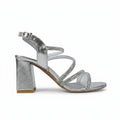 A single metallic silver high-heeled sandal with a block heel, strappy design, and iridescent rhinestone embellishments on the straps, shown against a light gray background.