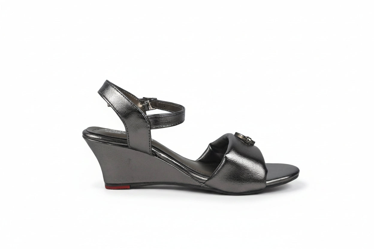 A metallic gray wedge sandal with an ankle strap and a small decorative buckle on the toe strap, shown from a side profile against a light gray background.