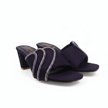 A pair of dark purple open-toe heeled sandals with glittery silver wrap-around straps, photographed on a white studio background.