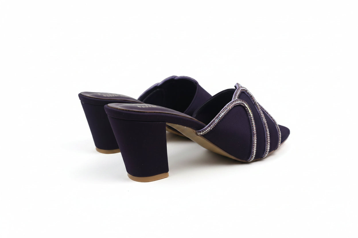 A pair of women's heeled mule sandals in deep purple velvet, featuring a pointed toe embellished with silver rhinestone straps and a chunky block heel.