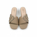 A pair of beige slide sandals with square toes and embellished straps featuring a curved design set with small clear rhinestones, shown on a light gray surface.