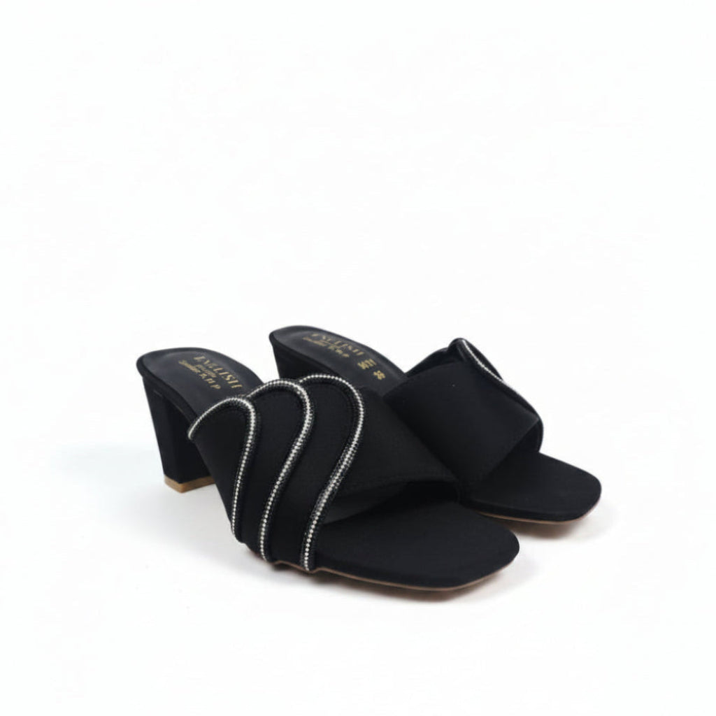 A pair of black heeled mule sandals with wide straps decorated with silver rhinestone-like trim, photographed on a plain light background.