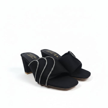 A pair of black heeled mule sandals with wide straps decorated with silver rhinestone-like trim, photographed on a plain light background.