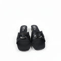 A pair of black leather slide sandals with square toes and wide straps featuring a prominent silver buckle, shown on a light gray surface.