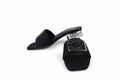 A pair of black slide sandals with chunky block heels and gold-tone metal hardware, displayed on a light gray surface.