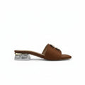 A single brown leather slide sandal with a clear acrylic block heel and a gold-tone buckle detail on the strap, shown against a light gray background.