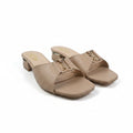 A pair of beige leather slide sandals with a low block heel and a gold-tone metal buckle detail on the strap, shown on a light gray studio background.