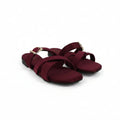 A pair of women's flat sandals in burgundy with gold-tone buckle details, displayed on a light gray studio background.