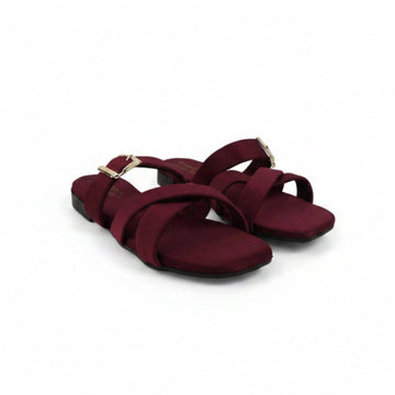 A pair of women's flat sandals in burgundy with gold-tone buckle details, displayed on a light gray studio background.