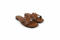 A pair of women's flat slide sandals in a warm brown leather, featuring a double strap design with a small central cutout, photographed on a white studio background.