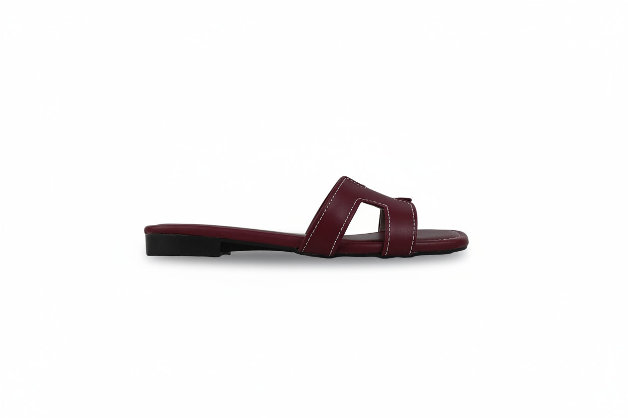 A single burgundy leather slide sandal with a cutout design on the toe strap, shown in profile against a light gray background.
