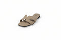 A single beige slide sandal with an H-shaped strap, photographed on a light gray studio background.