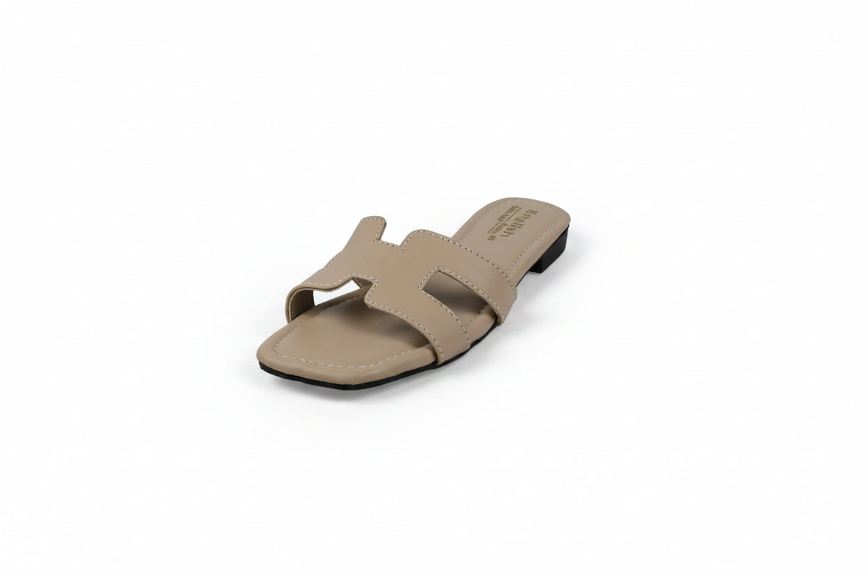 A single beige slide sandal with an H-shaped strap, photographed on a light gray studio background.