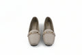 A pair of beige leather loafers with a gold-tone metal bar detail across the vamp, shown on a light gray background.