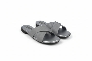 A pair of women's slide sandals in metallic silver with crisscrossing straps, shown on a light gray background.
