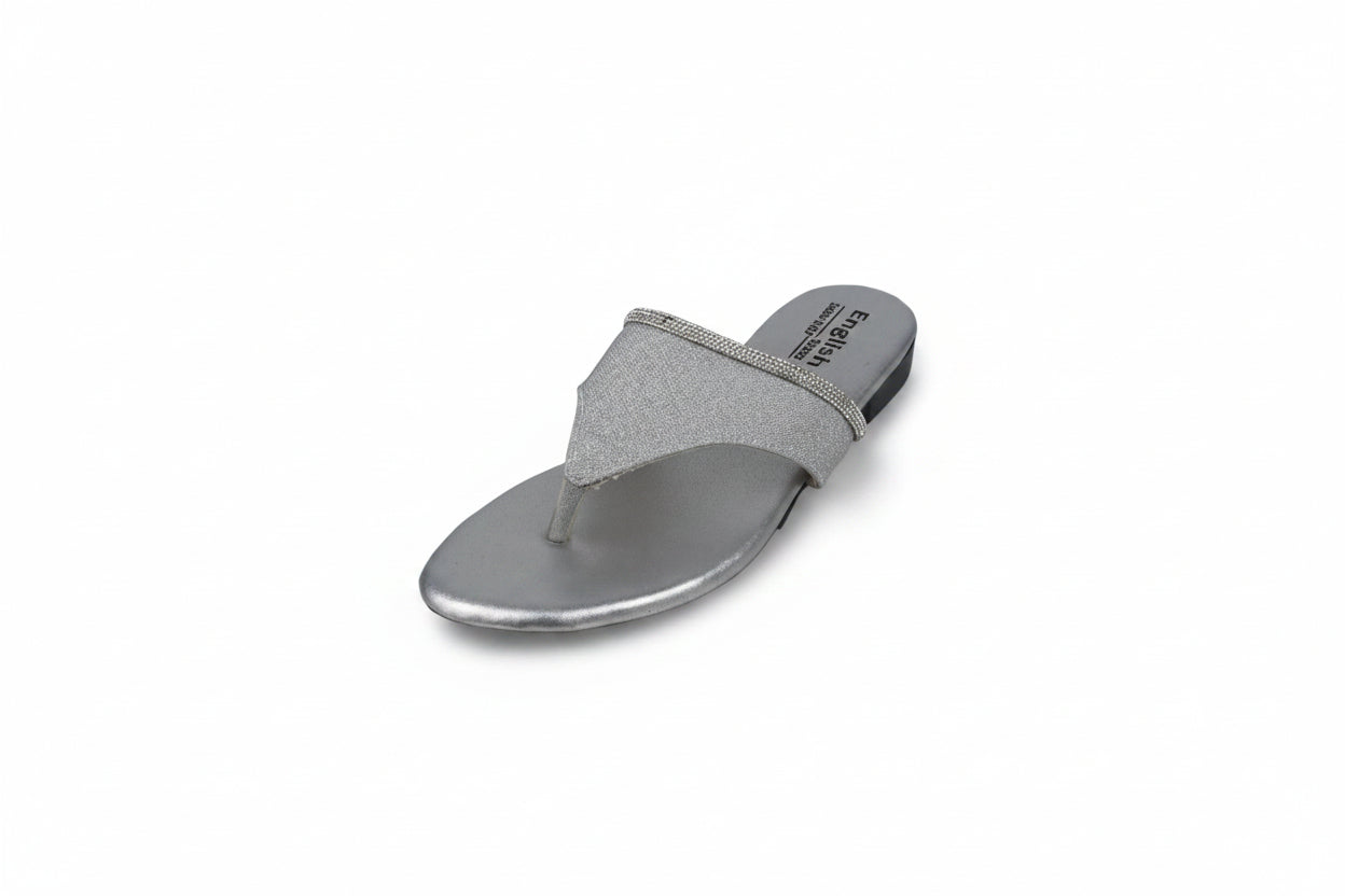 A single silver metallic thong sandal with a glittery strap and a low flat heel, photographed on a light gray background.