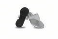 A pair of women's thong sandals with metallic silver glitter straps and silver footbeds, with one sandal turned upside down to show the black textured outsole.