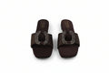 A pair of dark brown slide sandals with square toes and a prominent oval buckle embellished with sparkling rhinestones, shown on a light gray background.