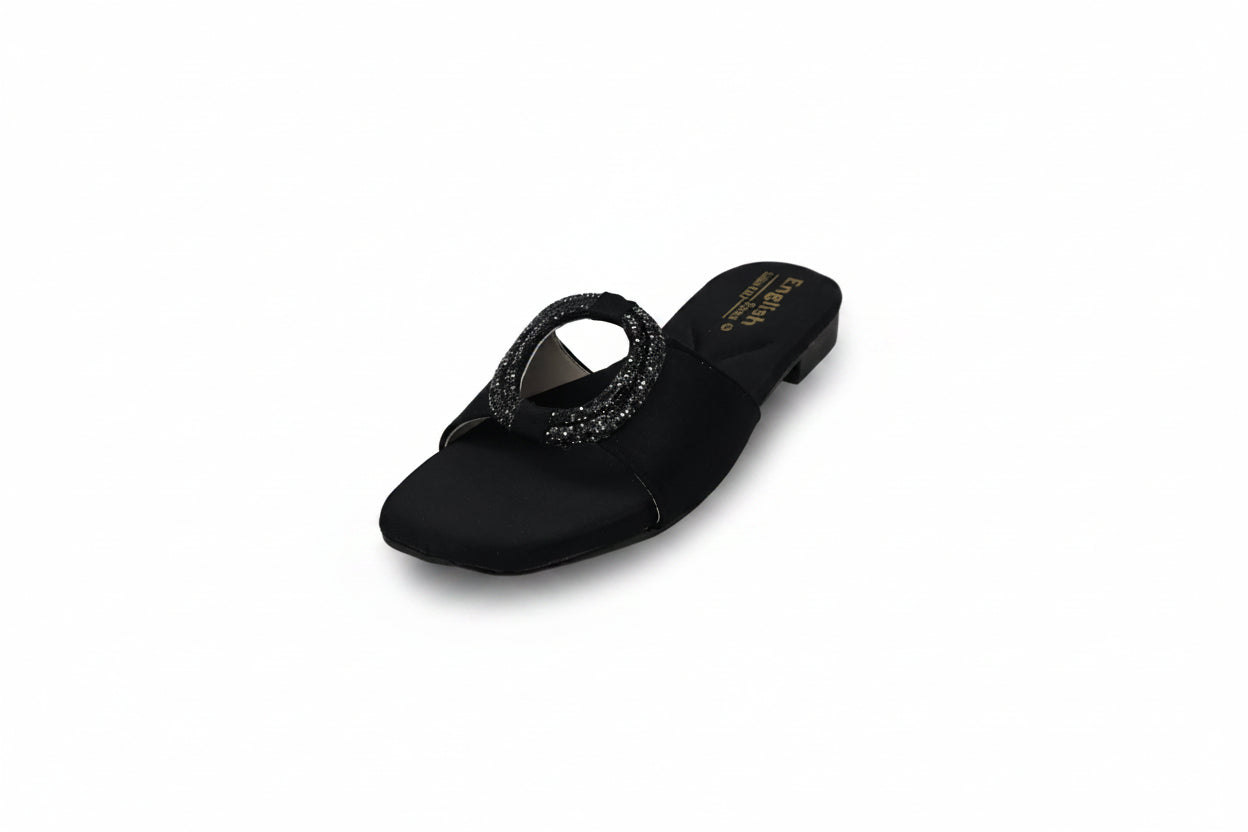 A single black flat slide sandal with a textured, sparkly circular toe strap, photographed on a light gray studio background.