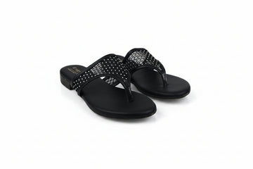 A pair of black slide sandals with rhinestone-embellished straps, photographed on a light gray studio background.