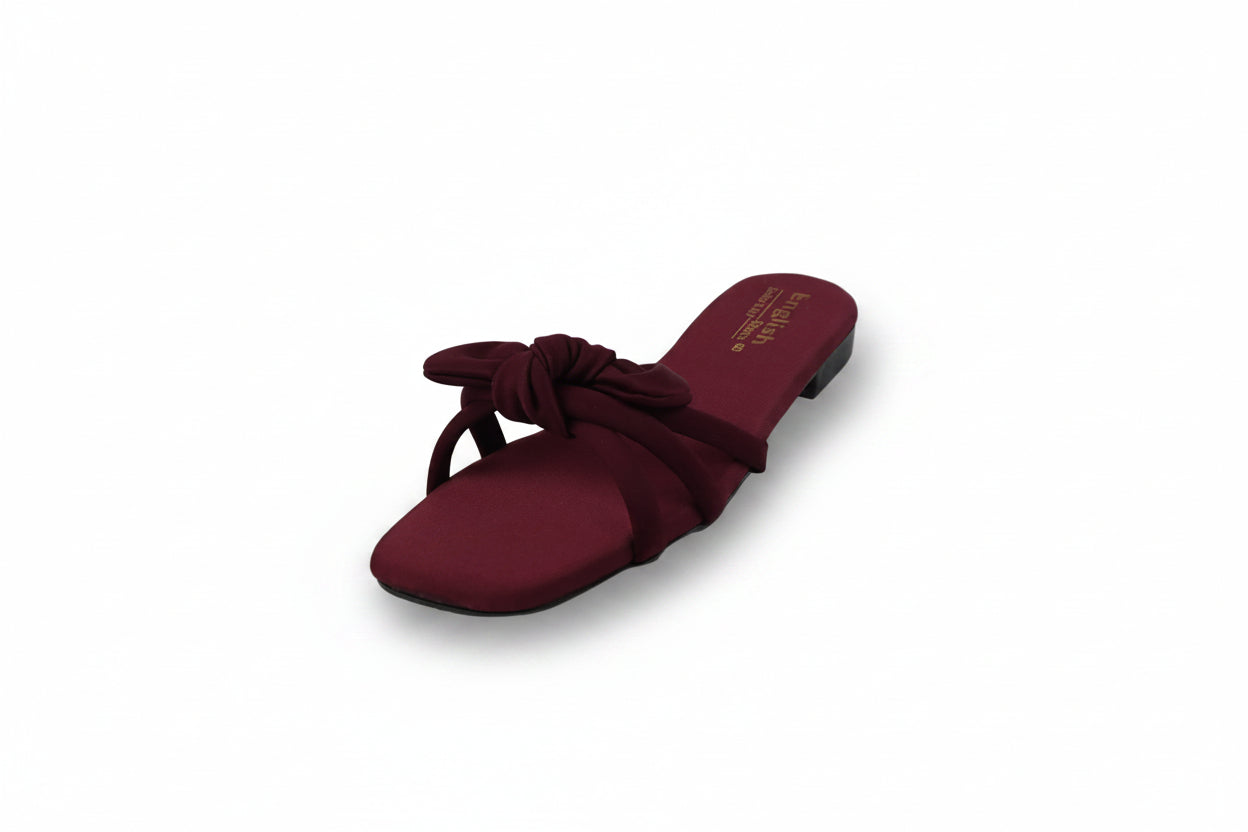A single burgundy flat slide sandal with a knotted bow detail across the instep, photographed on a white studio background.