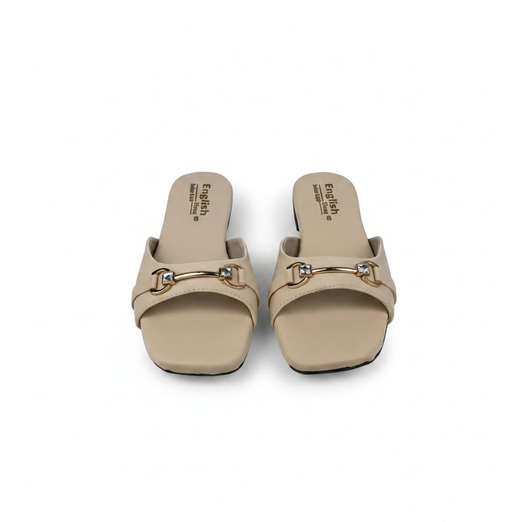A pair of beige slide sandals with gold-tone horsebit hardware and rhinestone accents, displayed on a light gray surface.