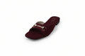 A single burgundy open-toe flat sandal with a gold horsebit detail across the instep, photographed on a light gray textured background.