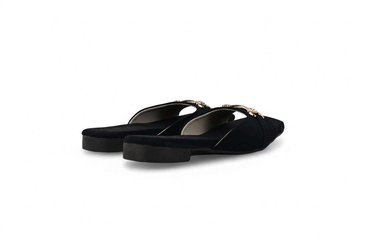 A pair of black pointed-toe flat mule sandals with thin straps and small gold-tone hardware, photographed on a light gray studio background.