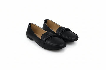 A pair of black leather penny loafers with a smooth strap across the vamp, displayed on a light gray floor.