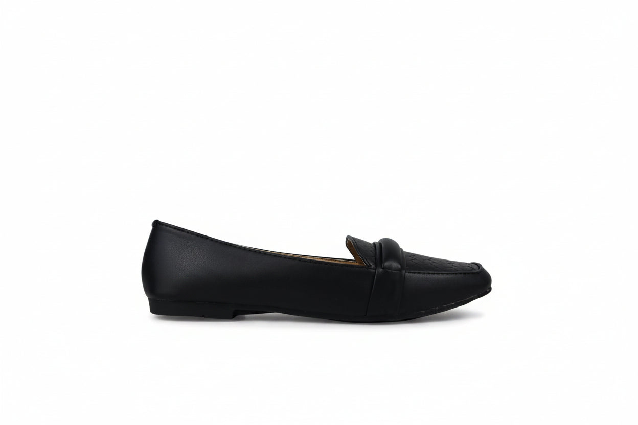 A single black leather penny loafer flat shoe shown in profile against a light gray textured studio background.