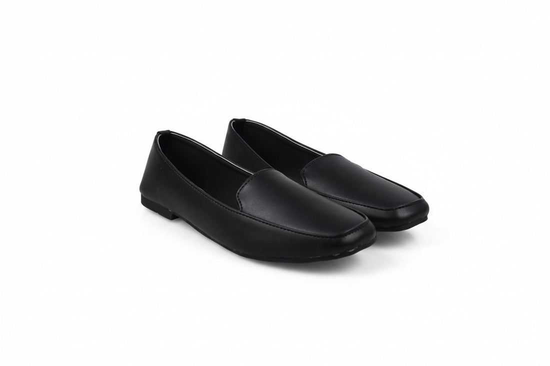A pair of black leather slip-on loafers with square toes, displayed on a light gray studio background.
