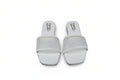 A pair of white slide sandals with rhinestone-embellished straps, shown from the top on a gray surface.