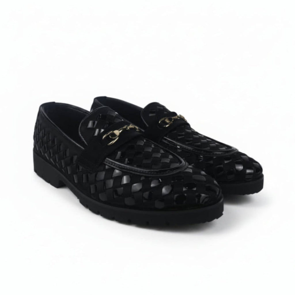 A pair of black woven leather loafers with a gold-tone horsebit detail on the strap, displayed against a light gray fabric backdrop.