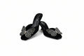 A pair of black velvet mule sandals with high heels, decorated with large silver butterfly embellishments on the front, set against a plain white backdrop.