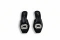 A pair of black mule sandals with clear rhinestone-embellished square toe caps, shown on a light gray surface.