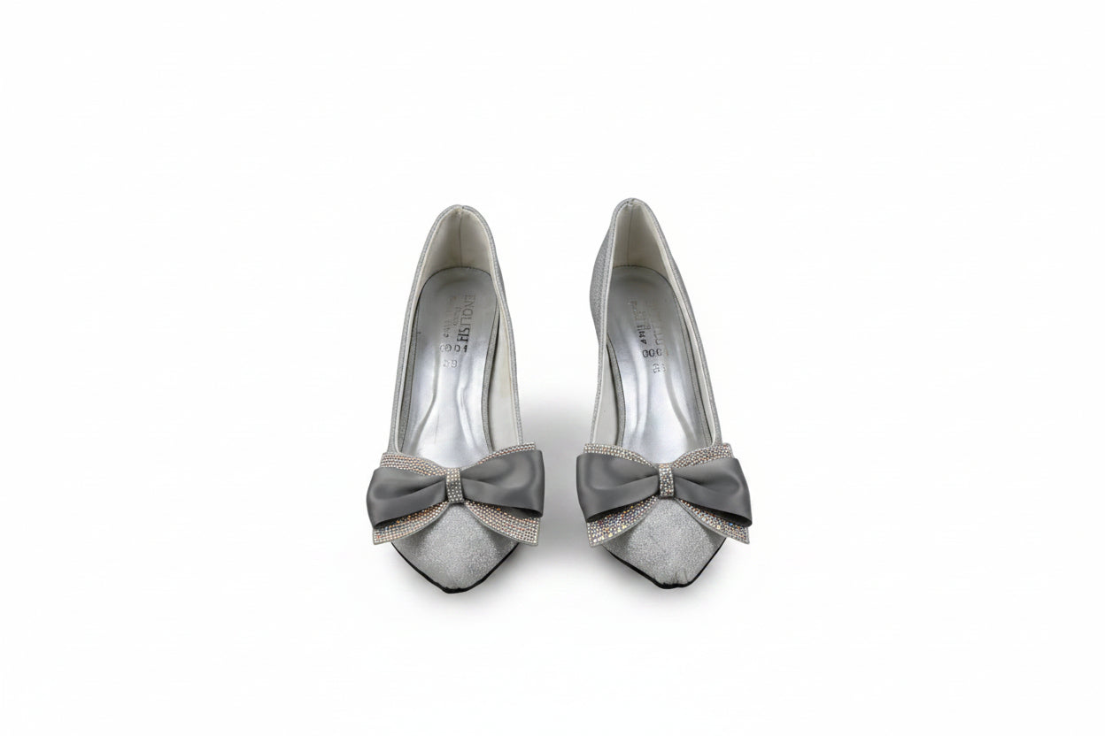 A pair of women's pointed-toe high heels in a light champagne or off-white color, featuring a wide gray satin bow with a rhinestone-embellished center on the vamp.