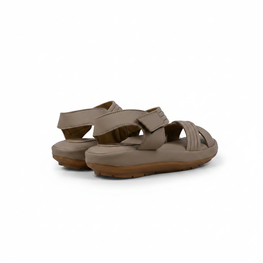 A pair of taupe-brown minimalist platform sandals with adjustable straps, displayed on a light gray surface against a matching backdrop.