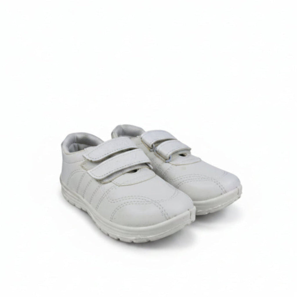 A pair of white children's low-top sneakers with double hook-and-loop straps, shown on a light gray textured studio background.